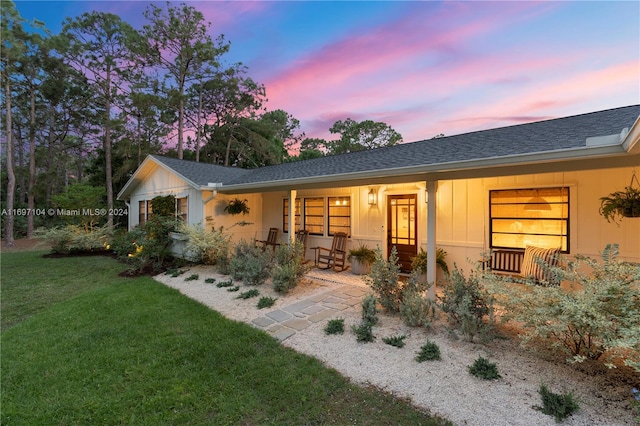 single story home with a yard and a porch