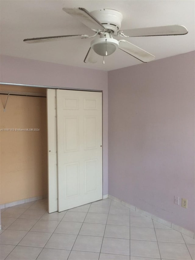 unfurnished bedroom with ceiling fan, light tile patterned floors, and a closet