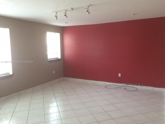 spare room with light tile patterned floors and rail lighting