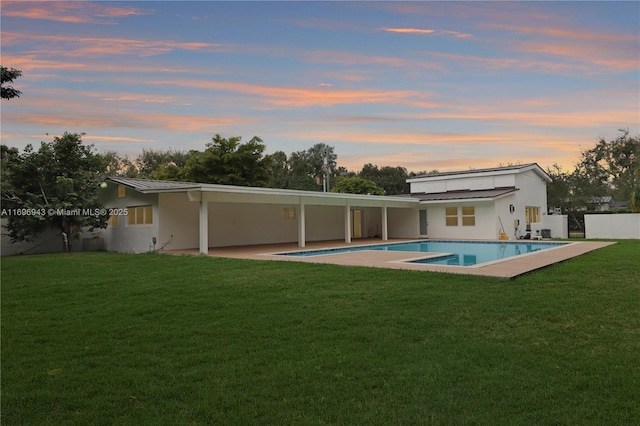 back house at dusk with a yard and a patio