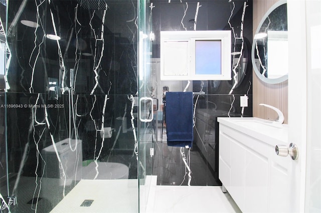 bathroom featuring a shower with door, vanity, and tile walls