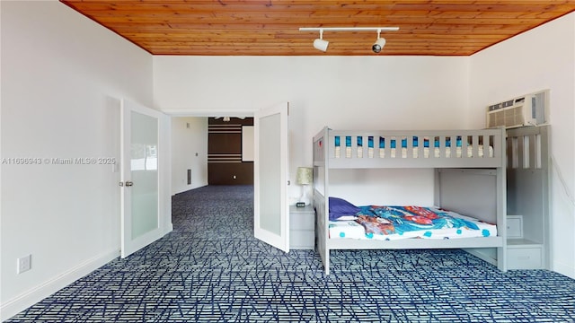 unfurnished bedroom featuring wood ceiling, rail lighting, and a wall mounted AC