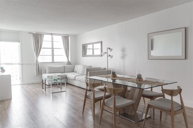 dining area with light wood-type flooring and a textured ceiling