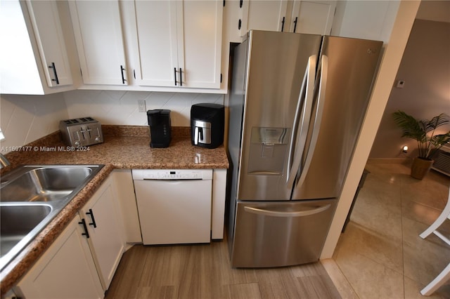 kitchen featuring white cabinetry, dishwasher, sink, stainless steel fridge, and decorative backsplash