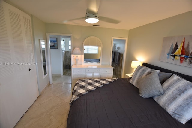 tiled bedroom featuring connected bathroom, ceiling fan, and a closet