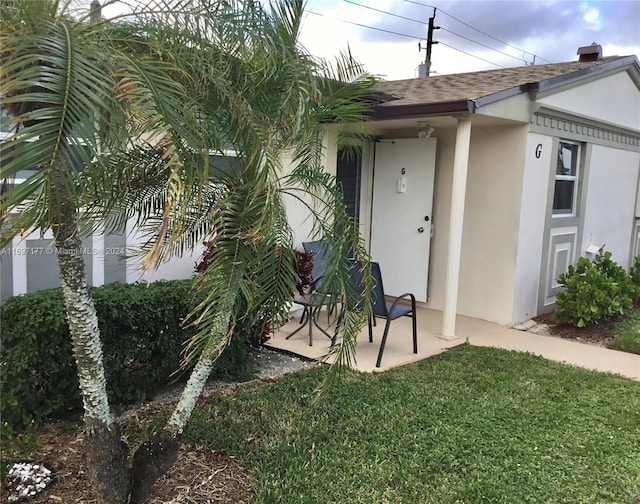 property entrance with a yard and a patio