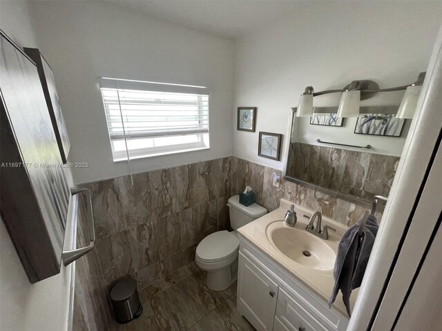 bathroom featuring vanity, toilet, and tile walls