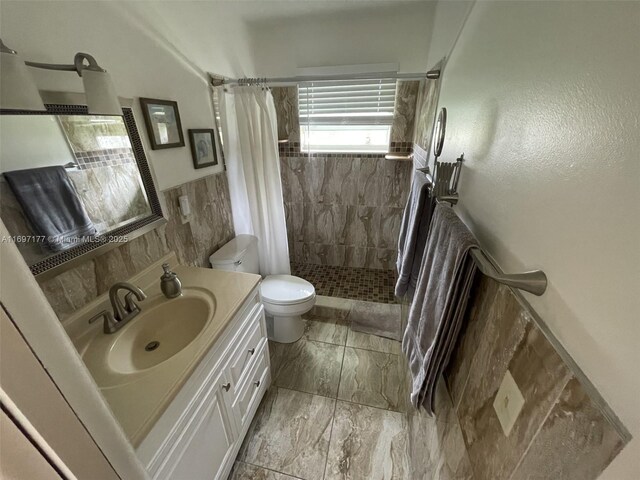 bathroom featuring a shower with curtain, vanity, toilet, and tile walls