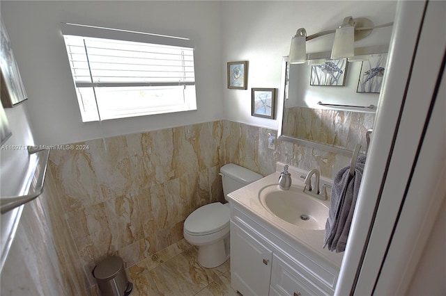 bathroom featuring vanity, toilet, and tile walls