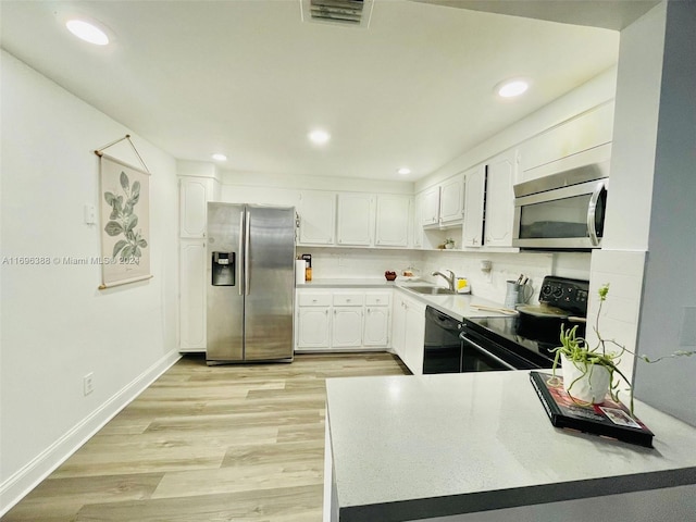 kitchen with backsplash, black appliances, white cabinets, sink, and light hardwood / wood-style floors