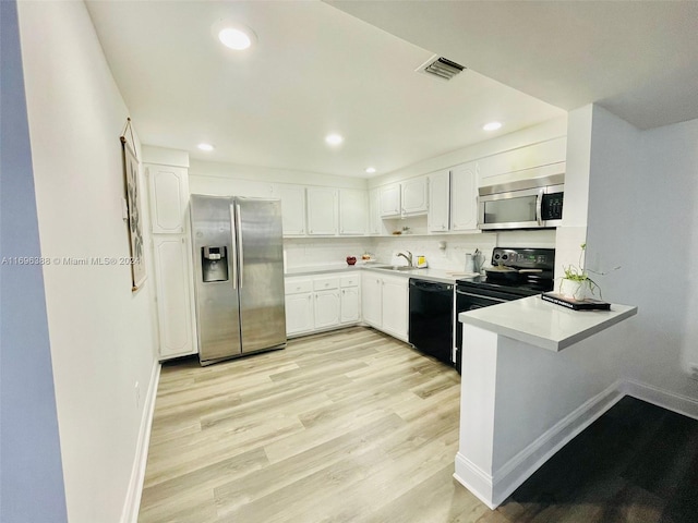 kitchen with light wood-type flooring, backsplash, sink, black appliances, and white cabinetry