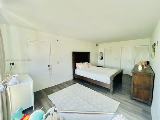 bedroom with dark hardwood / wood-style floors and multiple closets