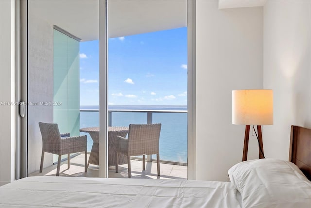 bedroom with multiple windows, a water view, and expansive windows