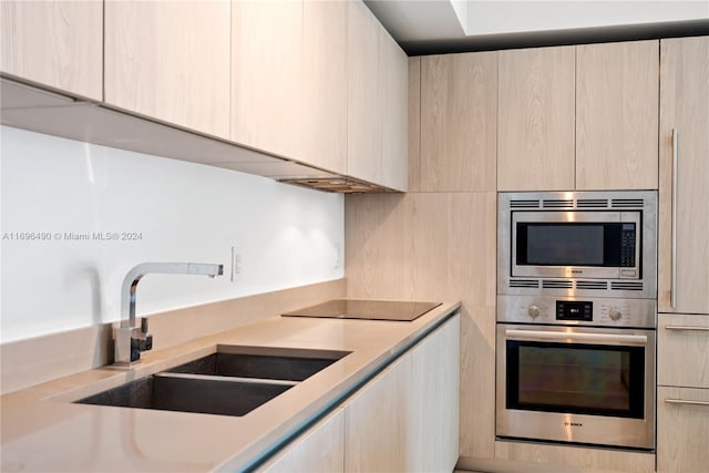 kitchen with light brown cabinetry, stainless steel appliances, and sink