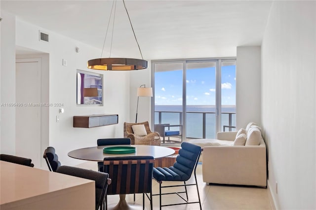 dining area featuring a water view and a wall of windows