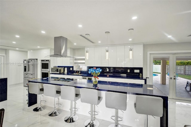 kitchen featuring french doors, sink, island range hood, pendant lighting, and white cabinets