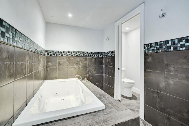 bathroom with tiled bath, tile walls, and toilet