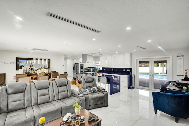 living room with bar, french doors, and a textured ceiling