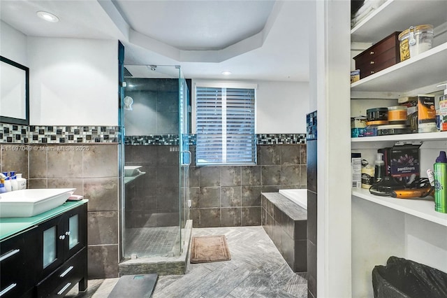 bathroom featuring plus walk in shower, tile walls, and vanity