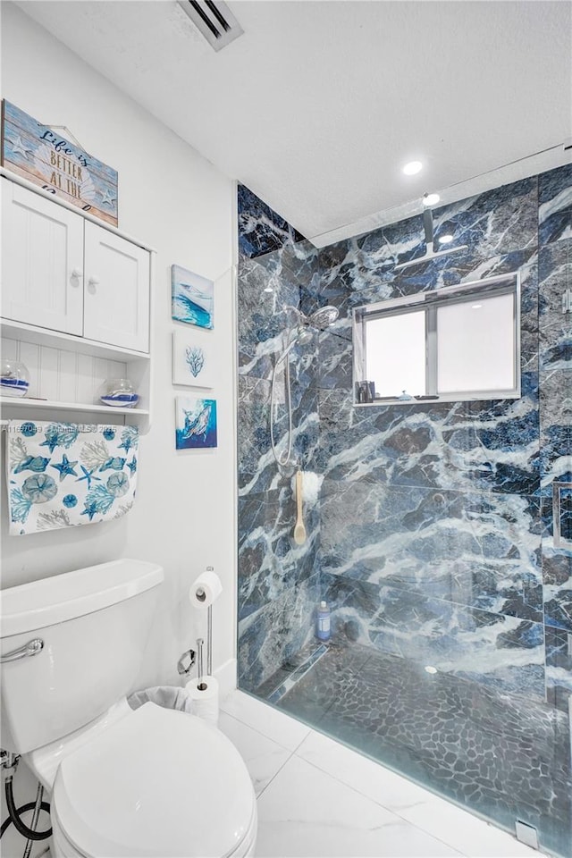 bathroom featuring a tile shower and toilet