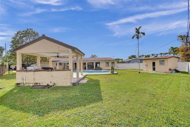 view of yard with an outbuilding, ceiling fan, a fenced in pool, and a patio area