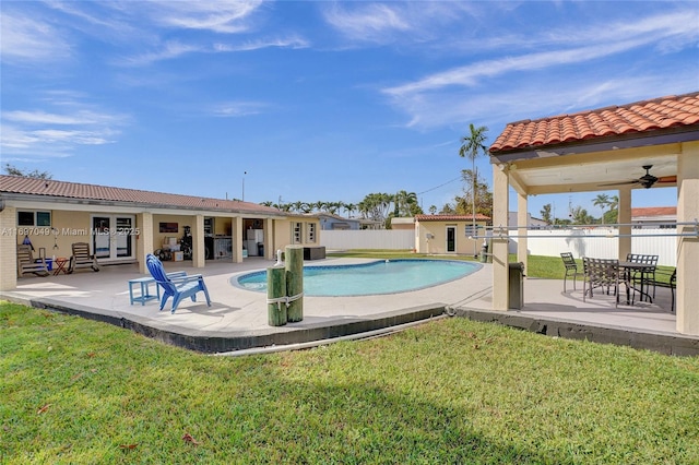 view of swimming pool with a patio, a lawn, an outdoor structure, ceiling fan, and french doors