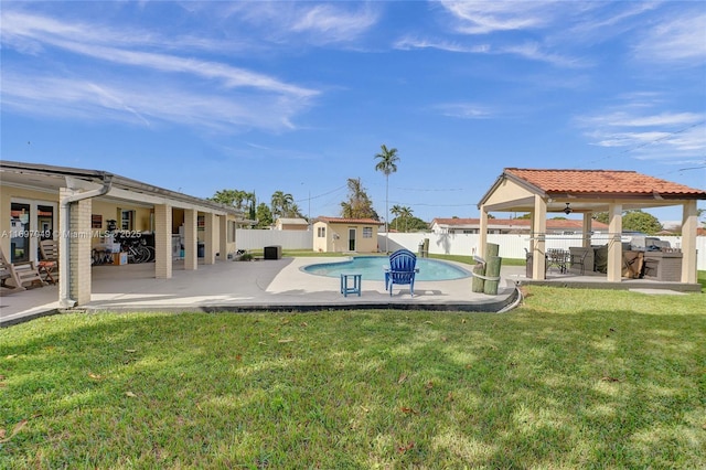 view of swimming pool featuring a patio, an outbuilding, ceiling fan, and a lawn