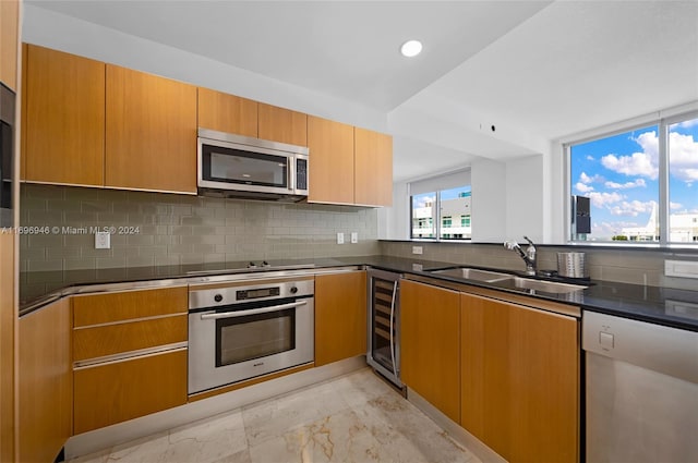 kitchen featuring backsplash, sink, beverage cooler, and appliances with stainless steel finishes