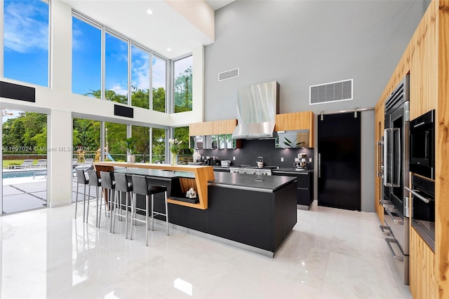 kitchen featuring a breakfast bar area, plenty of natural light, a kitchen island, and a high ceiling