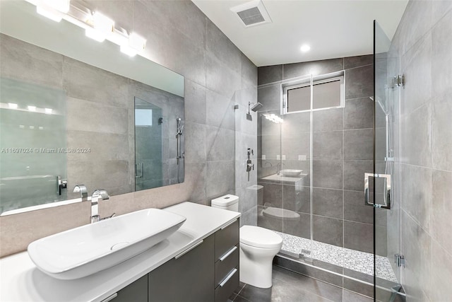 bathroom with tile patterned floors, an enclosed shower, toilet, vanity, and tile walls