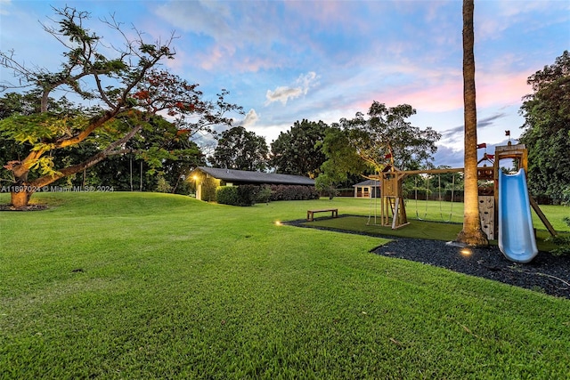 yard at dusk featuring a playground