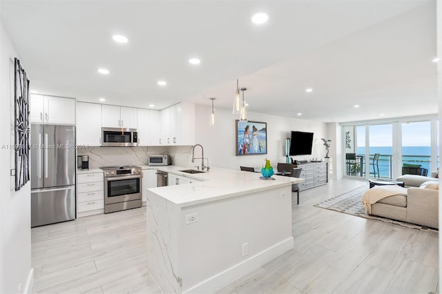 kitchen featuring white cabinetry, sink, stainless steel appliances, kitchen peninsula, and pendant lighting