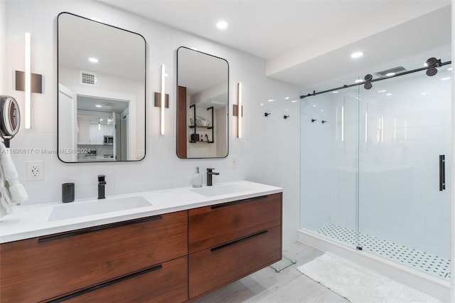 bathroom with vanity, a shower with door, and tile walls