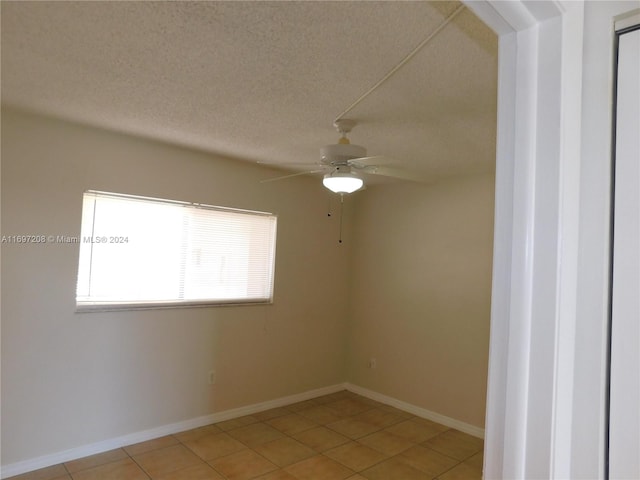 tiled empty room with ceiling fan and a textured ceiling