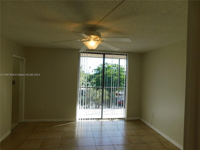 empty room featuring ceiling fan, light tile patterned flooring, and a textured ceiling