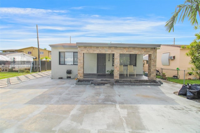 rear view of property featuring covered porch and a wall mounted air conditioner