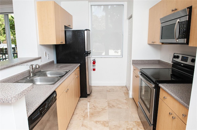 kitchen with appliances with stainless steel finishes, light brown cabinetry, and sink