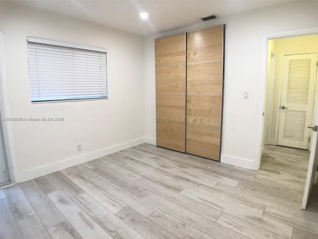 unfurnished bedroom featuring light wood-type flooring and a closet