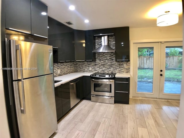 kitchen with french doors, light wood-type flooring, backsplash, wall chimney exhaust hood, and stainless steel appliances