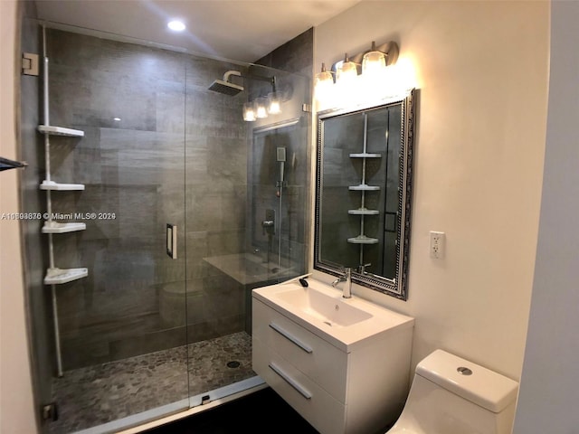 bathroom featuring vanity, toilet, and a shower with shower door