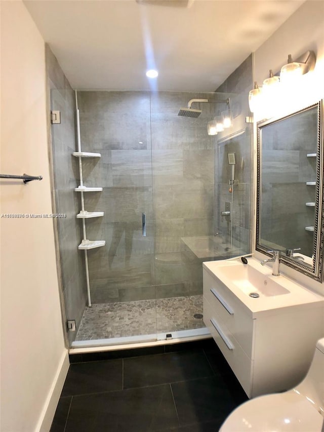 bathroom featuring tile patterned flooring, vanity, a shower with shower door, and toilet