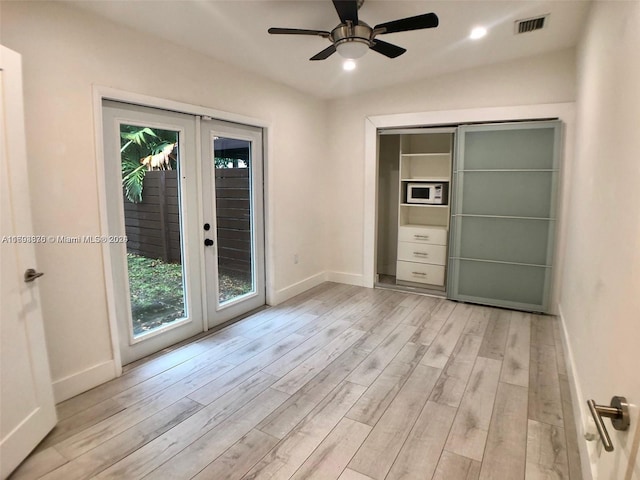 unfurnished room featuring french doors, light wood-type flooring, and ceiling fan