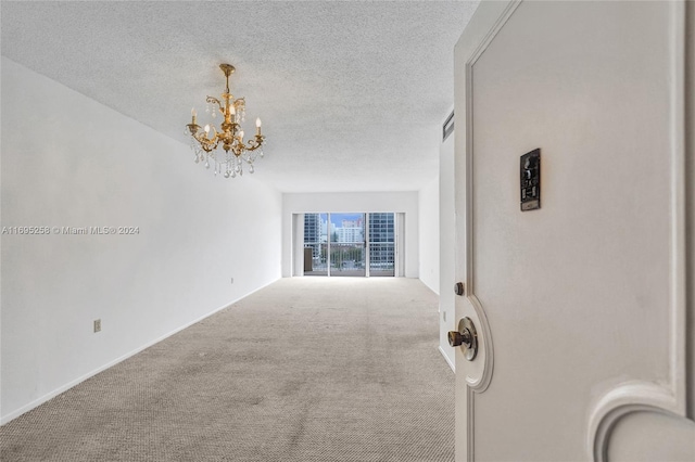 unfurnished living room featuring carpet, a textured ceiling, and a notable chandelier