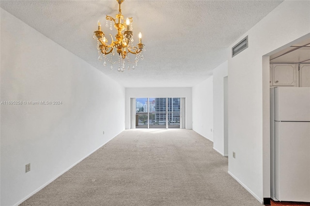 unfurnished living room featuring carpet flooring, a chandelier, and a textured ceiling