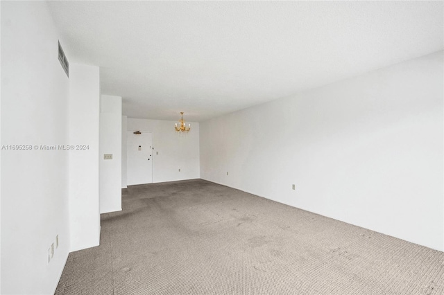 carpeted spare room featuring a notable chandelier