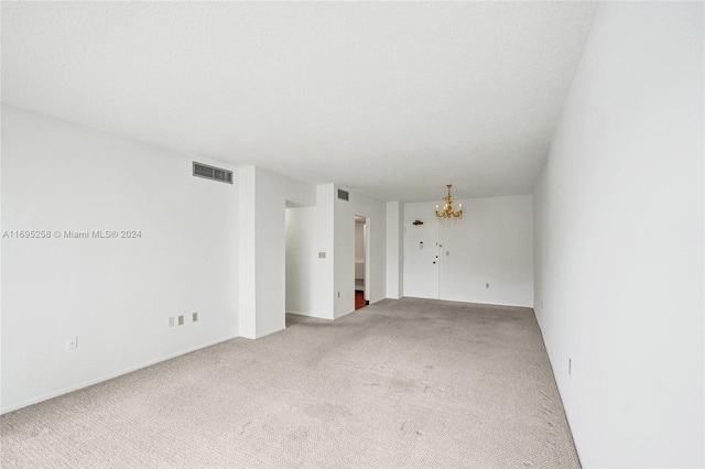 spare room featuring carpet flooring and a chandelier