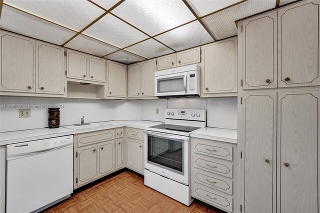 kitchen with white appliances, light parquet floors, and sink