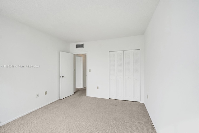 unfurnished bedroom featuring light carpet and a closet