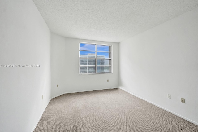 carpeted empty room with a textured ceiling