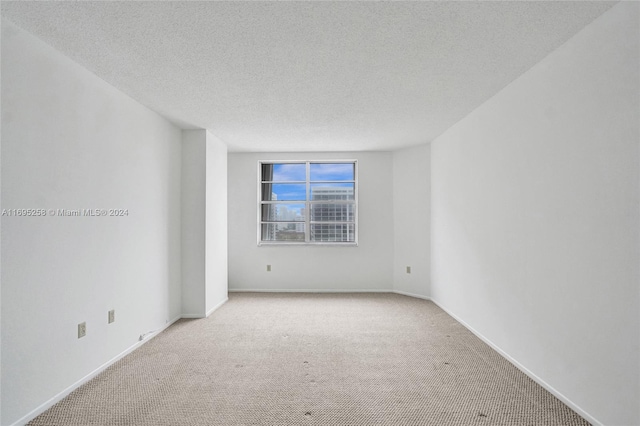 carpeted empty room featuring a textured ceiling